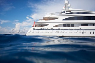 Side view of a superyacht in the mediterranean sea. Woman standing on deck  and leaning on railing looking at view