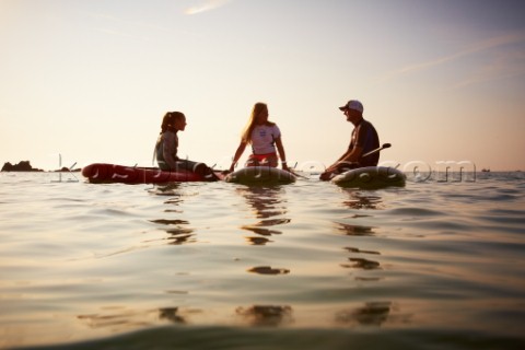 Two girls and a man sitting on paddleboards