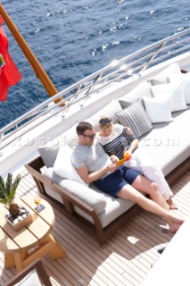 Couple sitting on sofa on deck of superyacht M/Y White Cloud