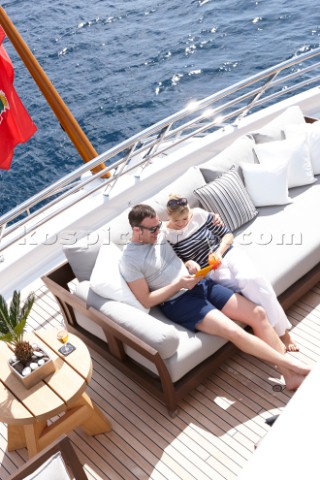 Couple sitting on sofa on deck of superyacht MY White Cloud