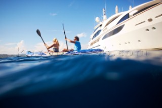 Couple kayaking near a superyacht
