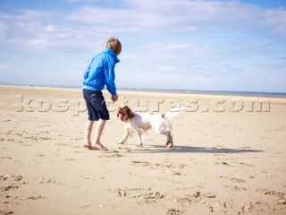 Boy playing with a dog on the beach