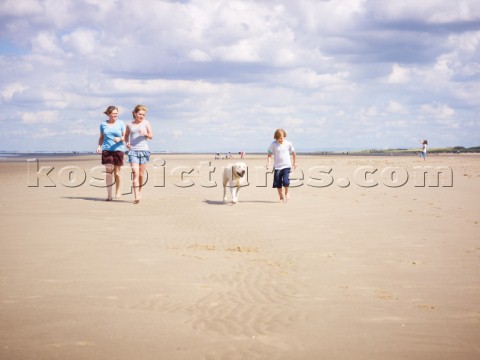 Family walking on the beach with a dog