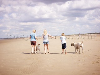 Family walking on the beach with a dog