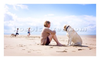 Woman sitting on beach with a dog