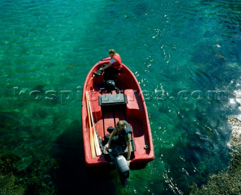 A couple sit aboard a little red speed boat on beautiful crystal clear water The Lofotens Arctic Cir