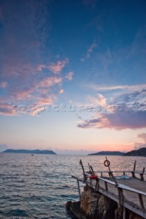 A wooden dock sticks out into the Mediterranean Sea at sunset in Kas, Turkey.