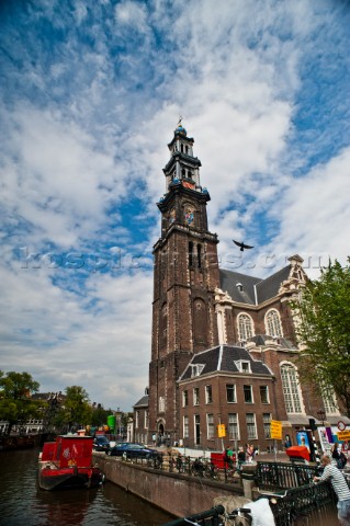 A bird flies by a church tower in Amsterdam Netherlands