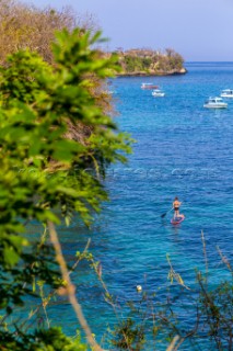 Woman travels by SUP surfboards at coastline of Nusa Lembongan and Nusa Ceningan islands, Indonesia.