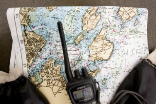 A chart and radio on board a sailing vessel, are at ready for navigation and communication purposes.