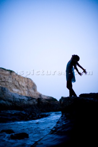Silhouetted portrait of Stephanie Crocker with her arms back like wings standing on a rock over the 