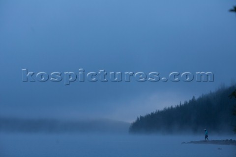 Moody image of a woman walking out on a point in Bowman Lake Glacier National Park Montana