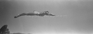 Lizbeth Zimmerman dives off a small rock cliff into Lake Pend Oreille near SAndpoint, Idaho. The image is a a grainy black and white panorami that looks like an old photograph