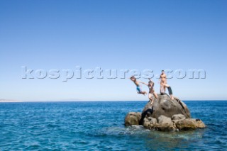 A mother and her three kids jump from an isolated rock into the Sea of Cortez in Baja California, Mexico. The image show the mother and one son watching as the daughter and other brother jump.The family was in Baja attending the wedding of the mothers sister at a nearby resort.