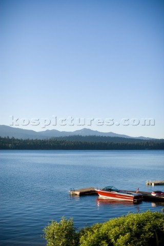 A red waterski boat is docked on a beautiful morning on Payette Lake near McCall Idaho