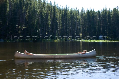 Two teenage boys create the illusion of one long person while lying down in an aluminum canoe in the