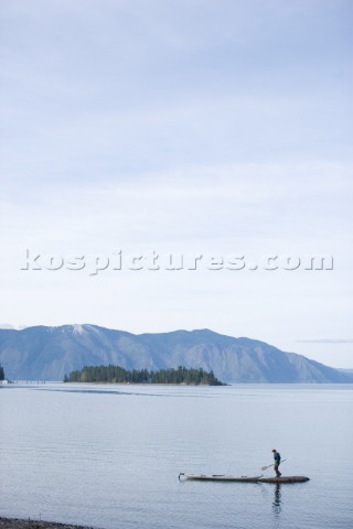 Woods Wheatcroft stops on a tiny rock island while sea kayaking on Lake Pend Oreille near Sandpoint 