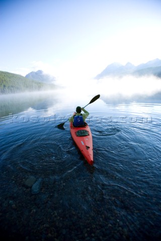 Andy Fueling paddles his kayak alone at dawn on Bowman Lake in Glacier National Park Montana