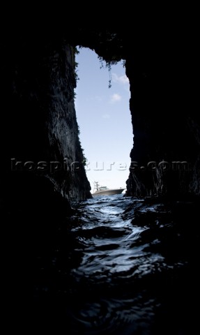 View of a boat floating in the water through the narrow opening of a dark cave in Costa Rica