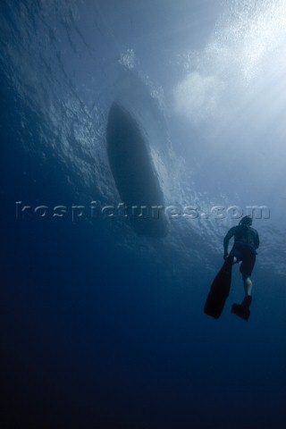 A view of a free diver underwater as he returns to the boat floating above in Costa Rica