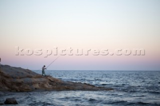 A man fishing at sunset in Calpe, Alicante.