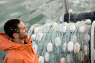 Joe Picha, deck hand on the Fishing Vessel Curragh, looks out to sea during a pause between fishing sets, fishing gear can be seen in the back ground, Naknek River fishing district, Bristol Bay, Alaska, USA 27th June 2008