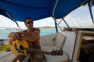 Captain Brian Carson takes a break from sailing the Nene to entertain his guests with a few songs, Hanalei Bay, Na Pali Coast, Kauai, Hawaii
