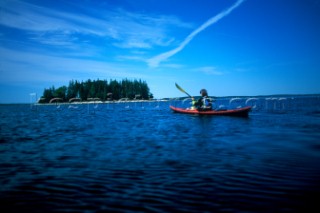 A woman paddles her sea kayak near Thief Island on Muscungus Bay, Maine. (releasecode: DM_MR1030)