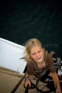 Young girl (6-7 years) climbing the rigging of a sailboat, Maine.