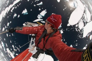 Man shoots a picture of himself as he climbs the mast of a ship in Antarctica and looks down from a great height.