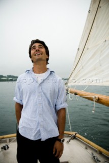 Man looking up at sails on sailboat, Casco Bay, Maine, New England. (releasecode: rausher and rausherPR)