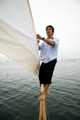 Man adjusts the sail on a sailboat Casco Bay Maine New England releasecode rausher and rausherPR