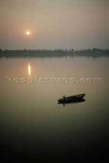 A boy gently guides a rowboat at dawn on the Ganges river near Varanasi.