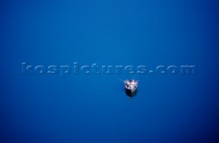A group of fisherman in a small boat float on the blue expanse of Walker Lake in central Nevada. The image shows an aerial type view of the fisherman that creates a sense of scale and space in the watery environment.