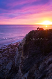 Setting up tent during sunset on the cliffs above the ocean on the central California coasat