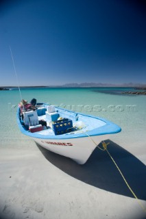 Blue and white mexican fishing boat is mored on the sand beach of the sea of cortez near Loreto, Mexico.