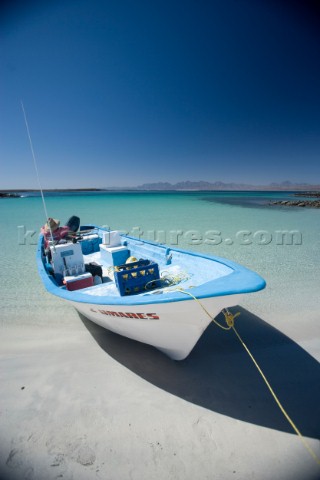 Blue and white mexican fishing boat is mored on the sand beach of the sea of cortez near Loreto Mexi