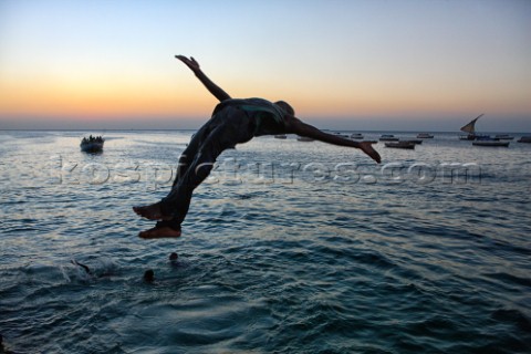 An unidentified boy jumps in the sea as the sun goes down  in the old stone town in Zanzibar Town Za