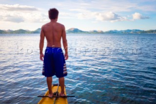 Filipino boatman standing on the bow of his outrigger boat, Coron, Palawan, Philippines