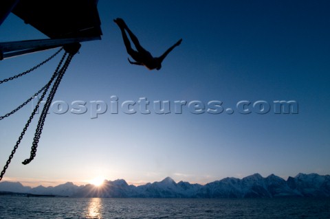 A man dives from a boat into the  Lyngen Fjord in northern Norways Lyngen Alps Kari MedigAurora Phot