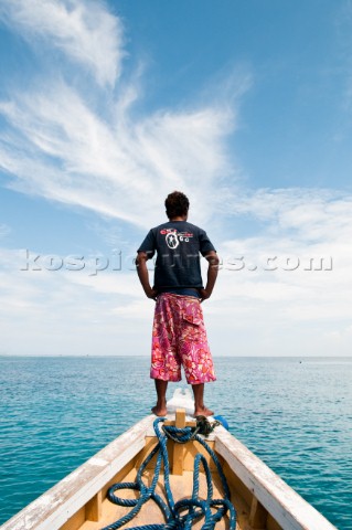 Rear view of an Indonesian man standing on a boat bow scanning the ocean near Gili Air Gili Island L