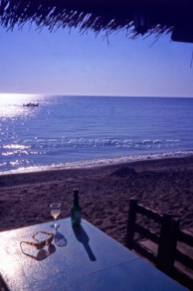 Greece. Lesvos. Glass of wine on a beachfront table. Skala Eressos. Steve Outram/Aurora Photos/Kos Pictures