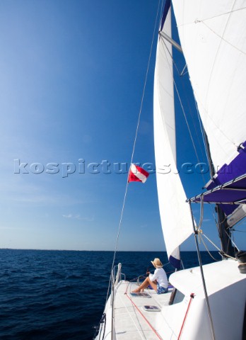 Ambergris Cay Belize A woman sits on the front of a catamaran while enjoying a cruise on the deep bl