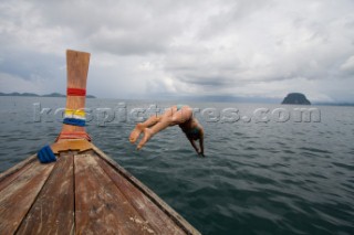 Female in bikini takes a plunge off of a longtail boat in Thailand.