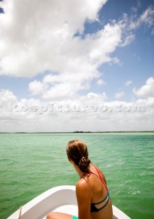 A young woman in a bikini sits in the bow of a white boat as it moves through teal-green water of the Sian Kaan Preserve. David Hanson/Aurora Photos/Kos Pictures